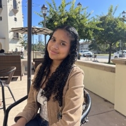 Alisah Brown sitting on the chair outside of the building smiling